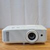 Compact white Optoma 1080p high-brightness projector available for rental, displayed on a wooden surface