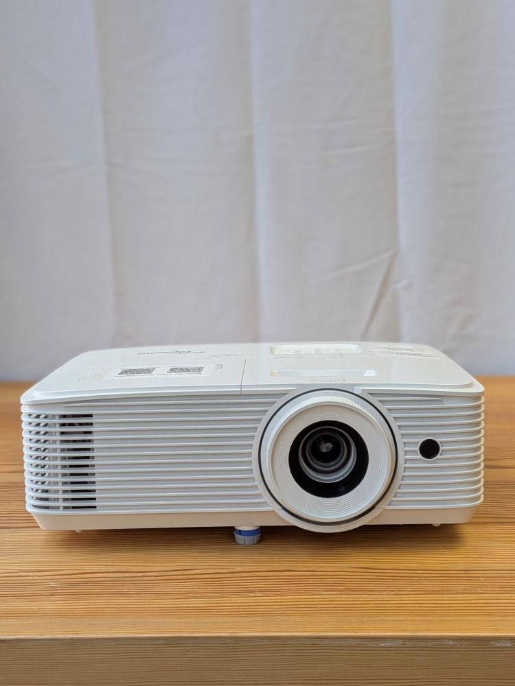 Compact white Optoma 1080p high-brightness projector available for rental, displayed on a wooden surface