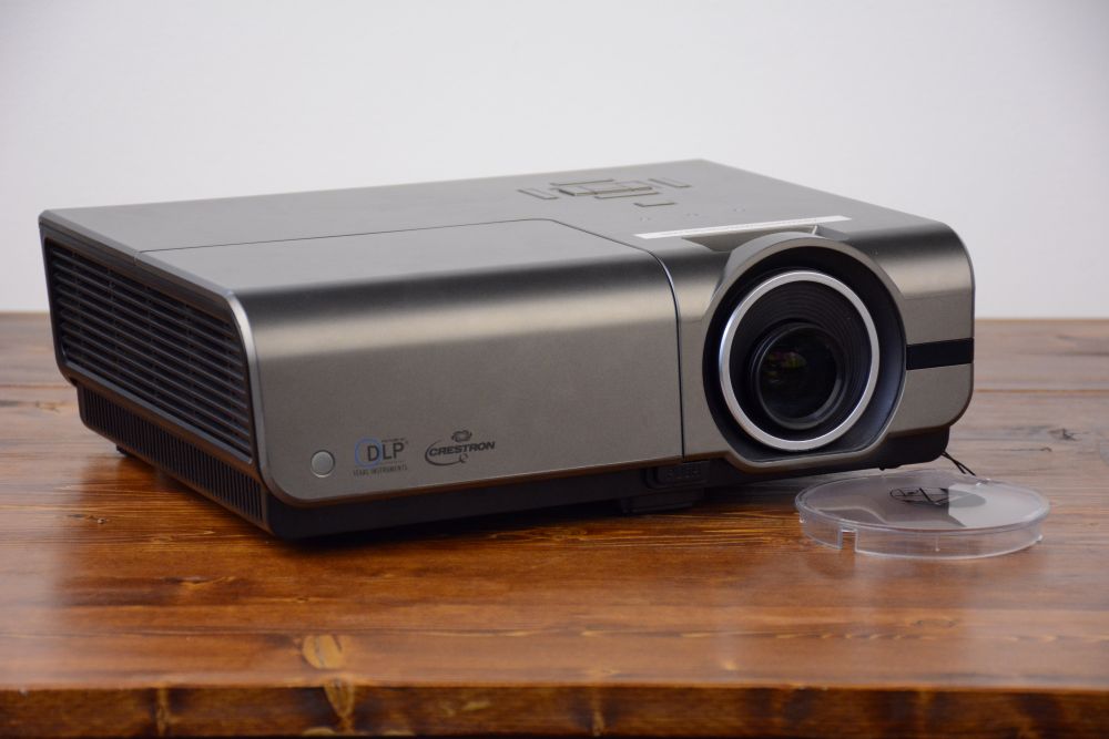 Professional high-brightness DLP projector rental unit with lens cap beside it, available for Vancouver events