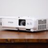 Compact Epson Full HD projector available for rental in Vancouver, displayed on a rustic wood table
