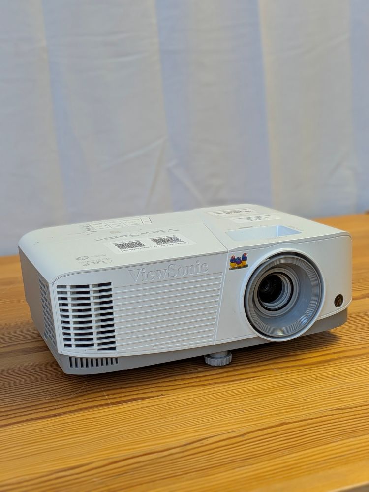 ViewSonic DLP projector rental unit shown from the front with lens and ventilation grille on a wooden surface