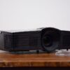 Compact black video projector rental with lens cap beside it, available for events in Vancouver