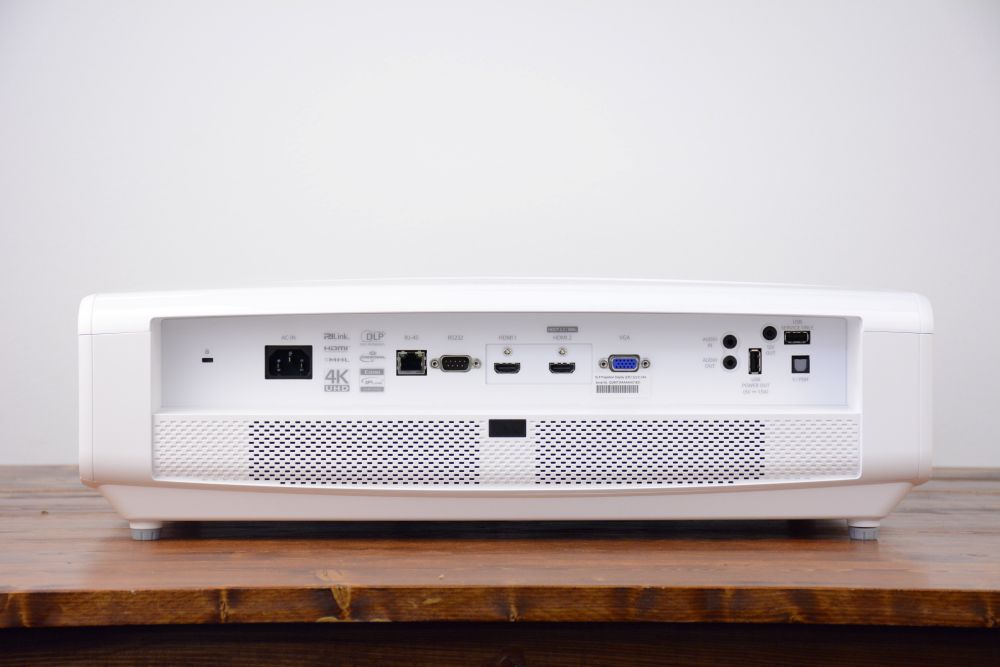 4K UHD projector rental rear input panel with HDBaseT, dual HDMI, VGA, and USB ports on a wooden surface