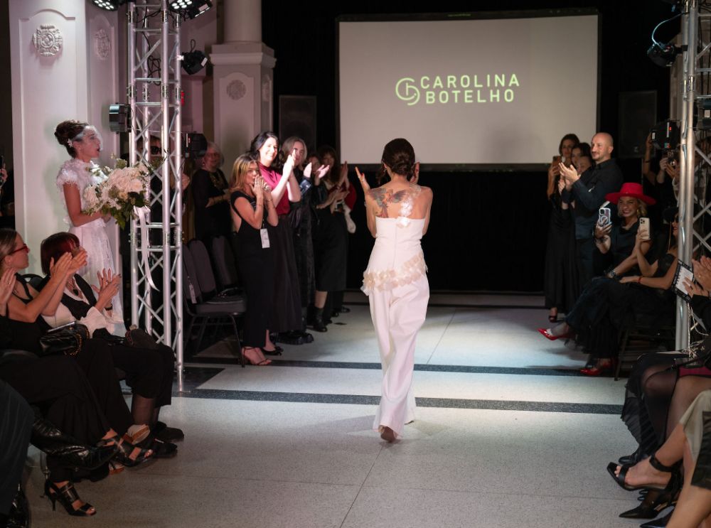 Professional event lighting casting a warm glow over the catwalk during a Carolina Botelho show finale