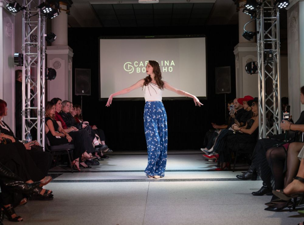 Professional event lighting rigs flanking a lit catwalk with a rear projection screen at a Vancouver runway show