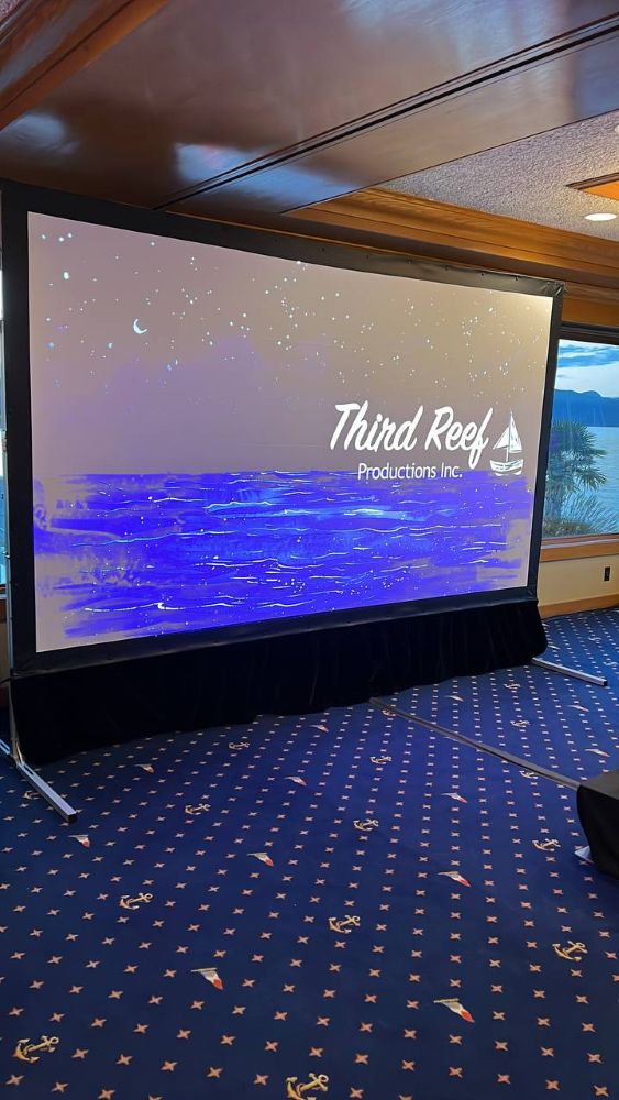Rental projection screen showing a night ocean scene with the Third Reef Productions brand logo in a waterfront venue