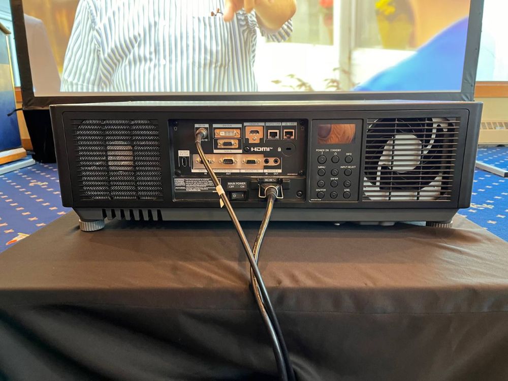 Close-up of a professional Panasonic projector rear connectivity panel with power and signal cables plugged in at a banquet venue