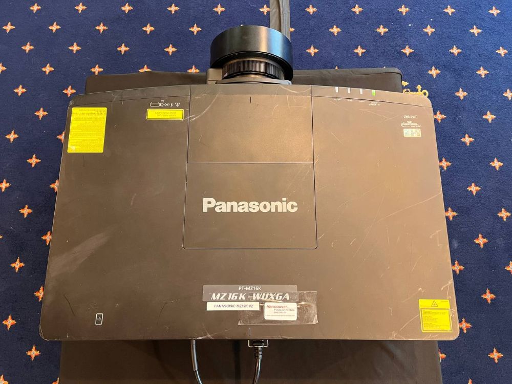 Close-up top-down shot of a Panasonic MZ16K professional laser projector with zoom lens mounted on top