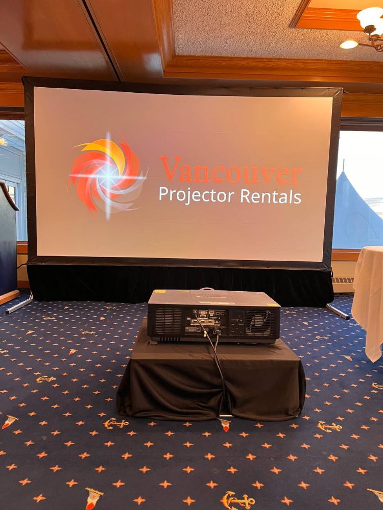Panasonic projector on a draped stand projecting the Vancouver Projector Rentals logo onto a large fast-fold screen in an event hall