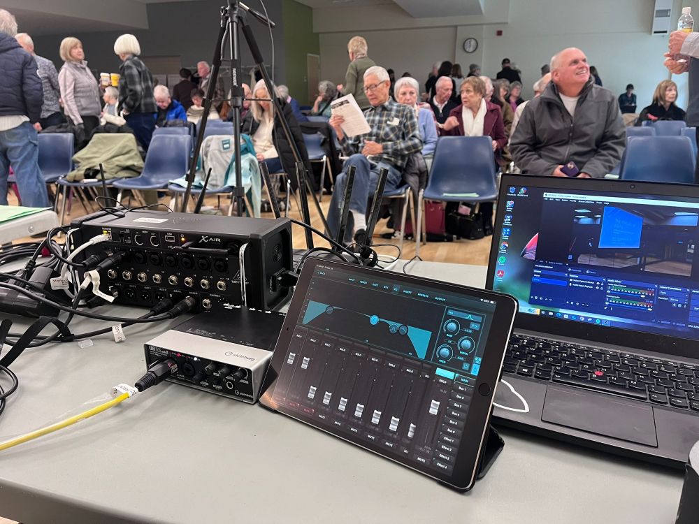 Close-up of hybrid livestreaming AV equipment including a digital mixer, audio interface, and tablet controller set up at a North Vancouver seniors conference