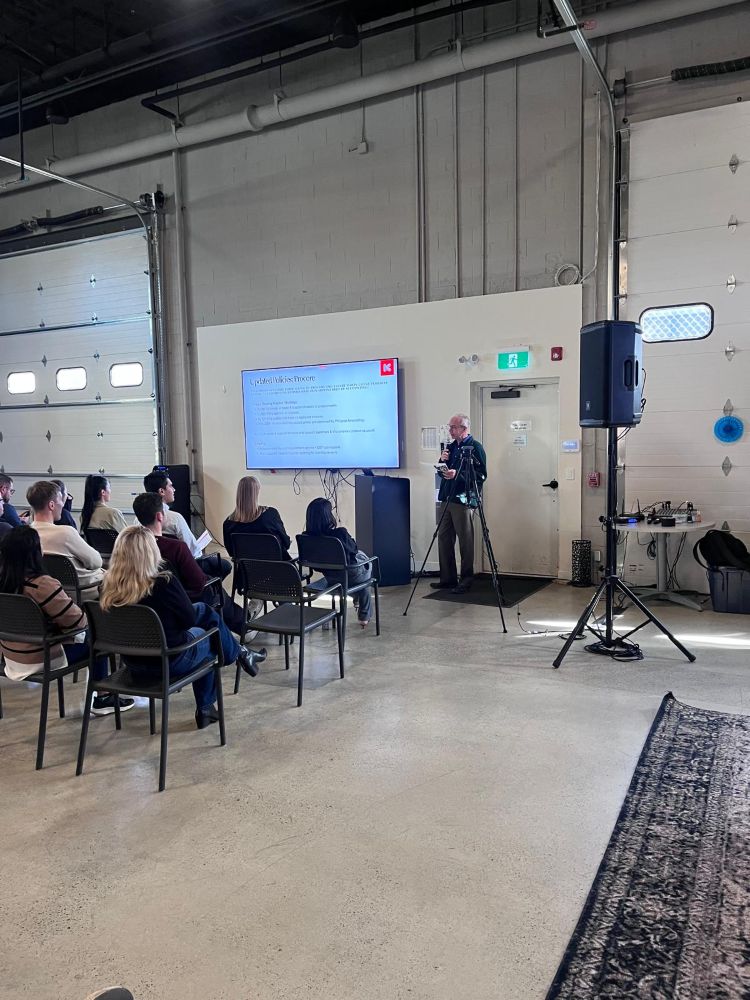Full room corporate event setup with TV screen rental, tripod-mounted speaker, and AV mixing station in an industrial event space