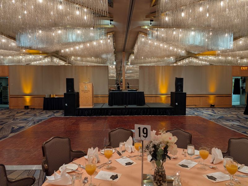 JBL EON 715 speakers on stands beside a black-draped fast-fold screen and podium before a school prom