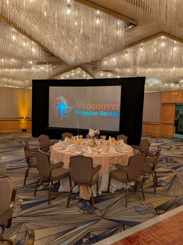 Vancouver Projector Rentals logo displayed on a 144x81 fast-fold screen during pre-event calibration at the Pan Pacific Hotel