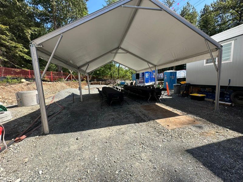 Wide view of an event tent with audio equipment and seating set up on an active construction site for an 80-guest crew presentation